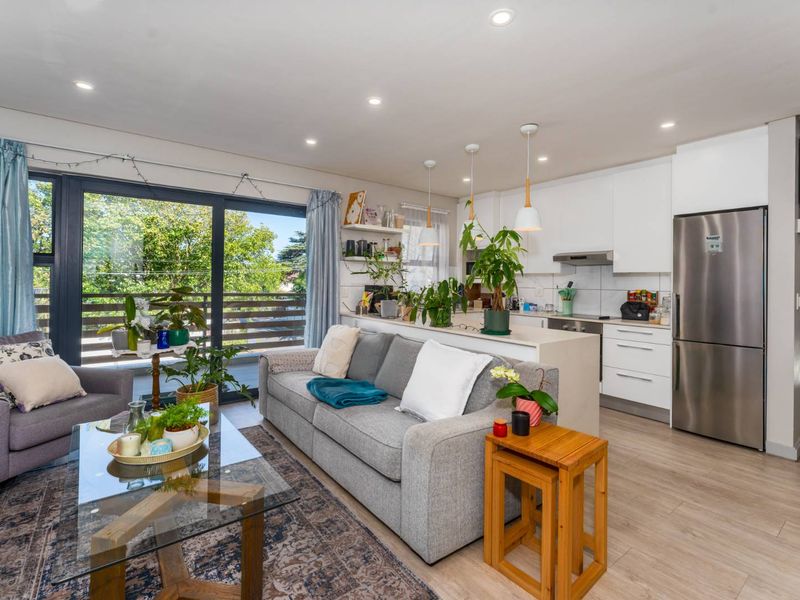 Modern open-plan living area featuring a sleek kitchen with built-in cabinetry and a seamless transition to a private balcony through large sliding glass doors.