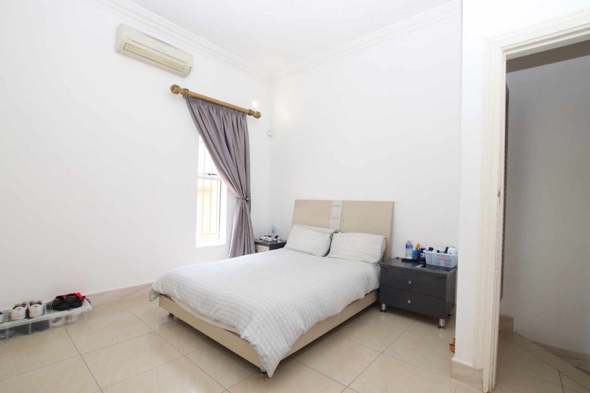 A bright bedroom featuring tiled flooring, crown molding, and a wall-mounted air conditioning unit.