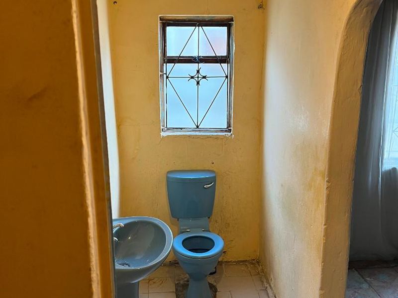 A dated bathroom featuring a blue pedestal basin and toilet, requiring significant renovation and cosmetic updates to improve the overall condition and aesthetic.