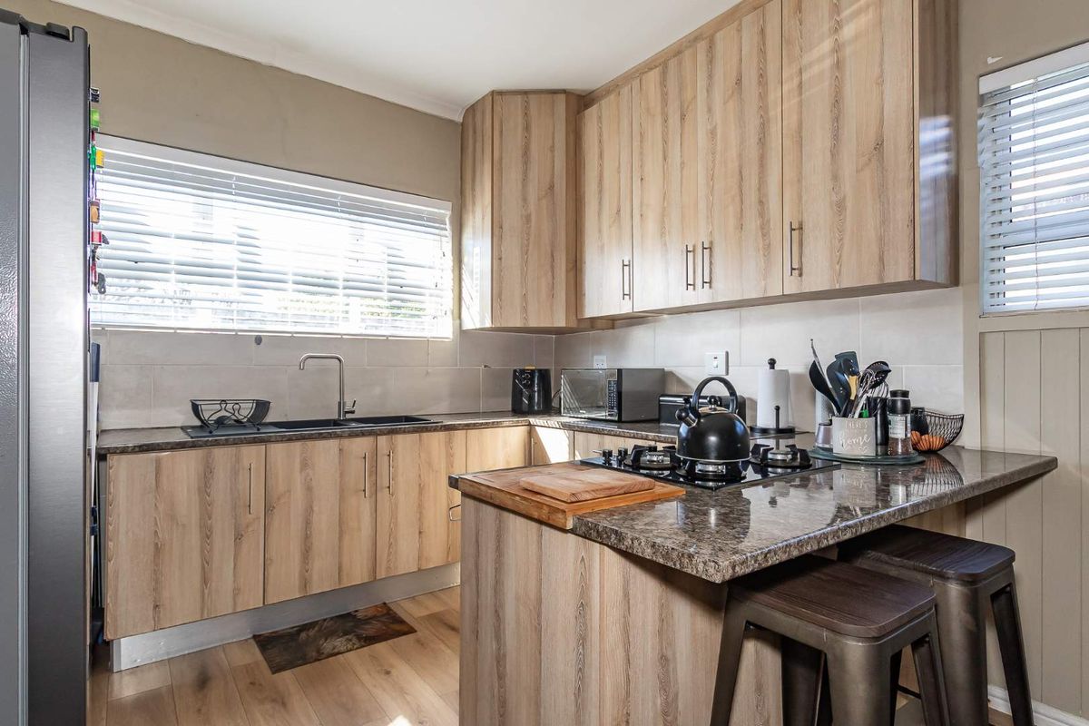 Modern kitchen featuring wood-look laminate cabinetry, granite countertops, a gas hob, and a functional layout with ample storage and natural light.