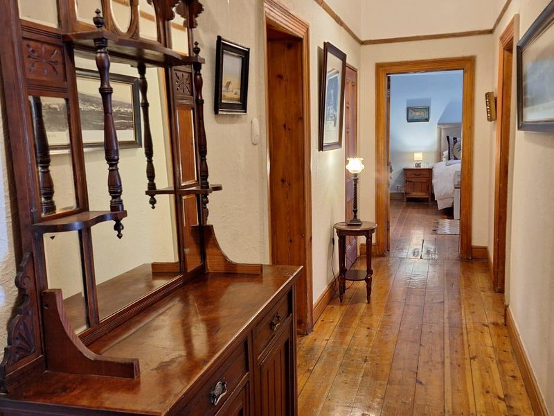 A well-maintained hallway featuring polished timber flooring and classic wooden door frames, providing access to adjacent rooms within the property.