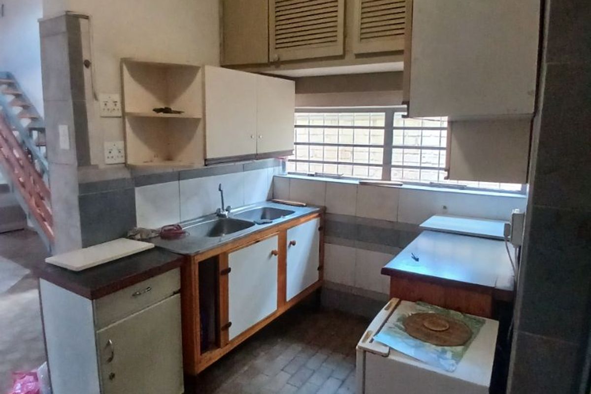 A dated kitchen featuring original built-in cabinetry, a double basin sink, and tiled backsplash, offering significant potential for a modern renovation.