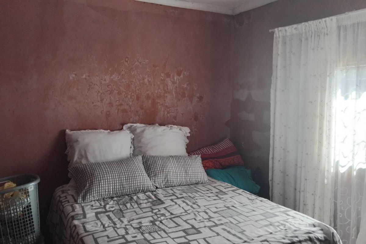 A bedroom featuring a textured wall finish with visible staining and discoloration, requiring cosmetic attention.