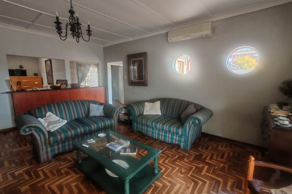 A living room featuring classic parquet flooring, distinctive circular windows, and a wall-mounted air conditioning unit.