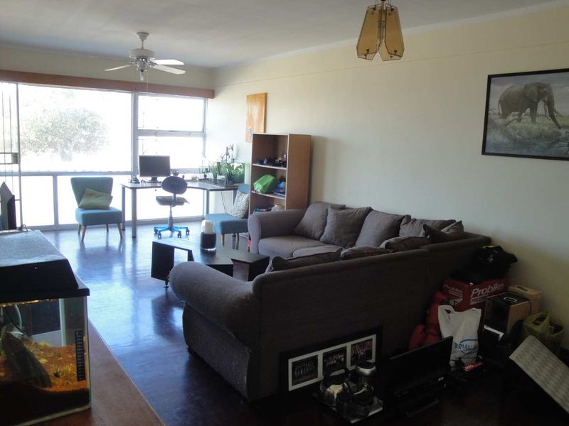 Spacious living room featuring large sliding glass windows that provide ample natural light and laminate flooring throughout.