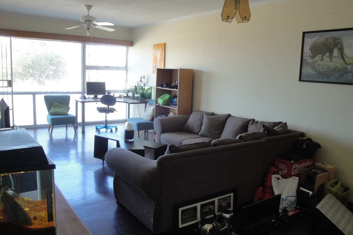 Spacious living room featuring large sliding glass windows that provide ample natural light and laminate flooring throughout.