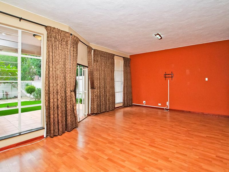 Spacious living room featuring laminate flooring, a bold accent wall, and large sliding glass doors providing direct access to the outdoor patio area.