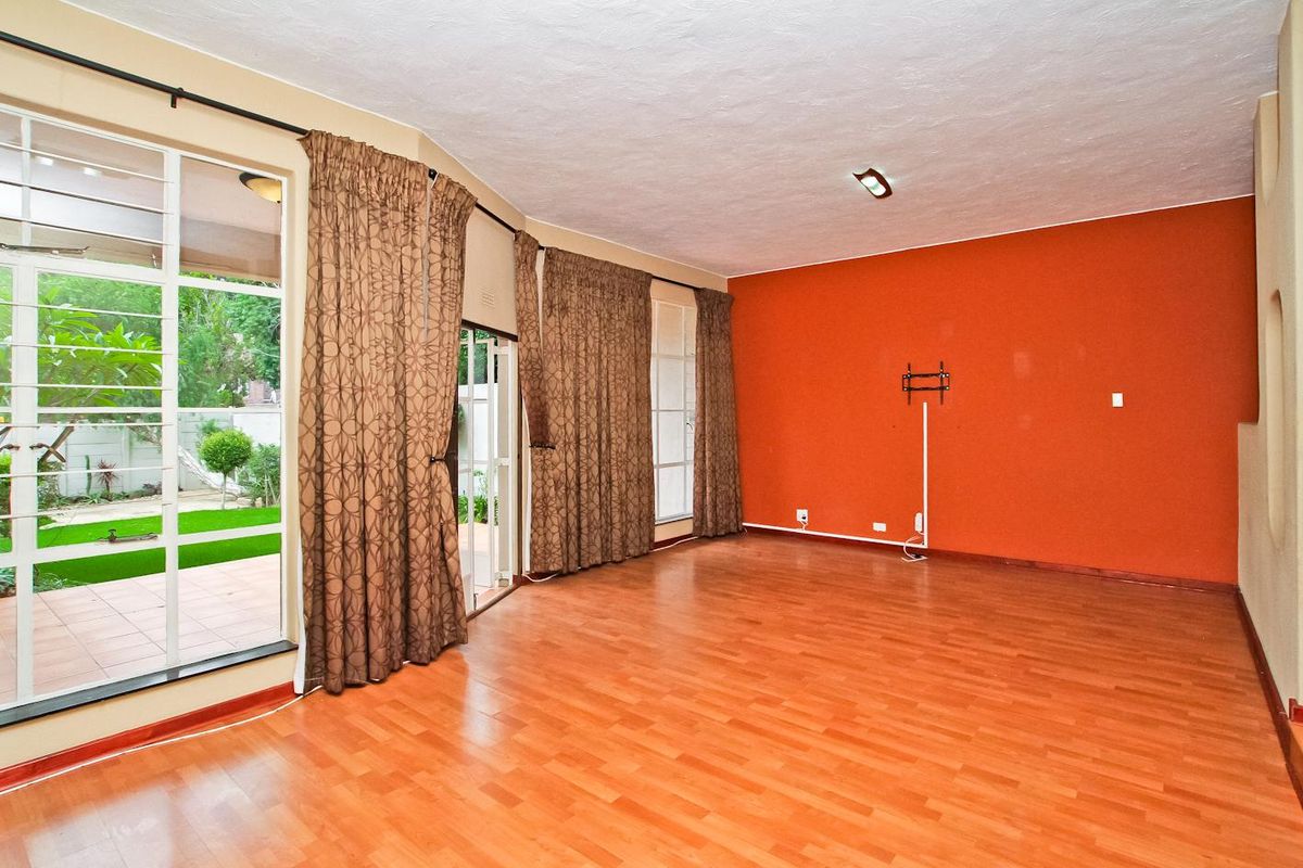 Spacious living room featuring laminate flooring, a bold accent wall, and large sliding glass doors providing direct access to the outdoor patio area.