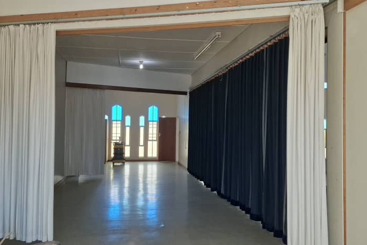 A large, open-plan interior space featuring sliding room dividers, arched windows, and functional lighting, suitable for versatile use in a mixed-use property.