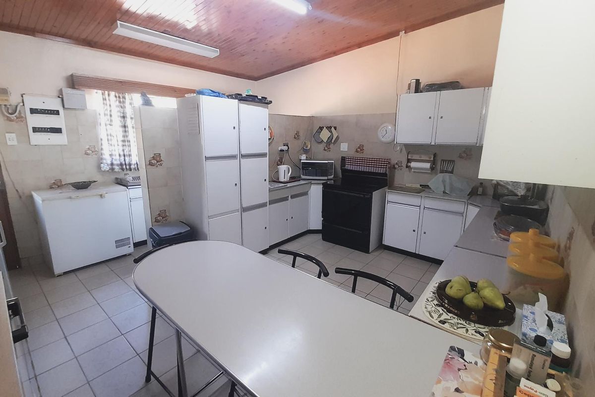 A functional kitchen featuring tiled flooring, timber ceiling, built-in cabinetry, and a tiled splashback, offering a dated aesthetic ready for modernization.