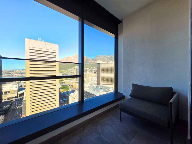A bright interior space featuring expansive floor-to-ceiling windows that offer a panoramic urban and mountain view.