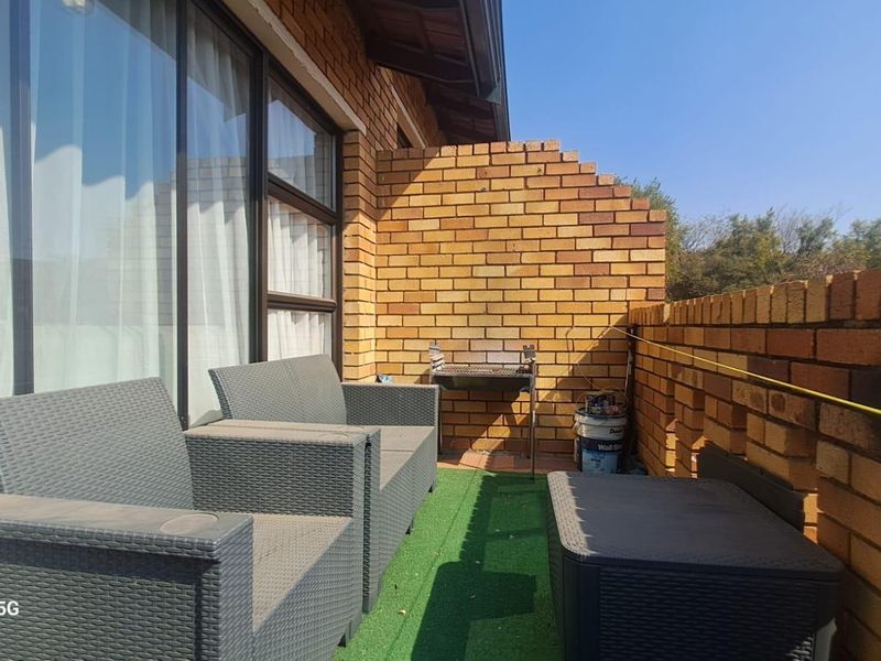 A private balcony featuring exposed brick walls, a built-in braai, and direct access to the interior through large sliding glass doors.