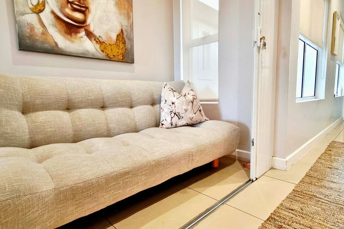 A bright living area featuring neutral tiled flooring and a sliding door track, creating a clean and functional transition space.