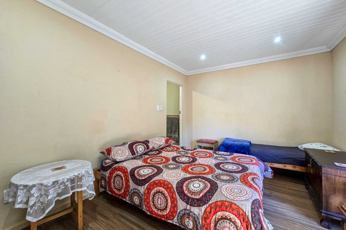 A bedroom featuring laminate flooring and a white tongue and groove ceiling with recessed lighting.
