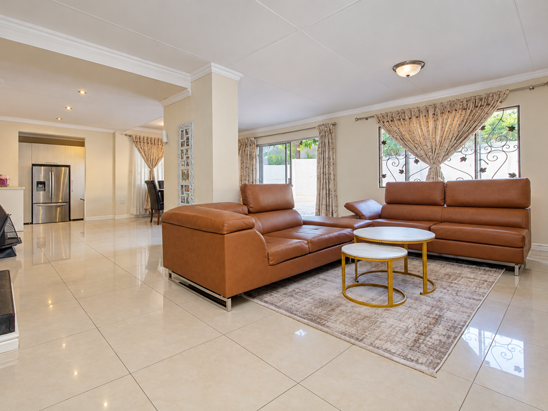 Spacious open-plan living area featuring polished porcelain tiles, a modern freestanding fireplace, and seamless flow into the adjacent kitchen and dining space.