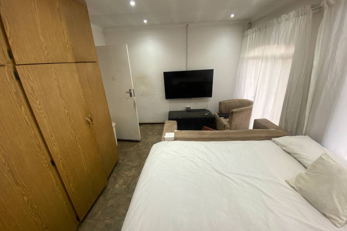 A bedroom featuring built-in wooden cabinetry, tiled flooring, and recessed ceiling lighting.