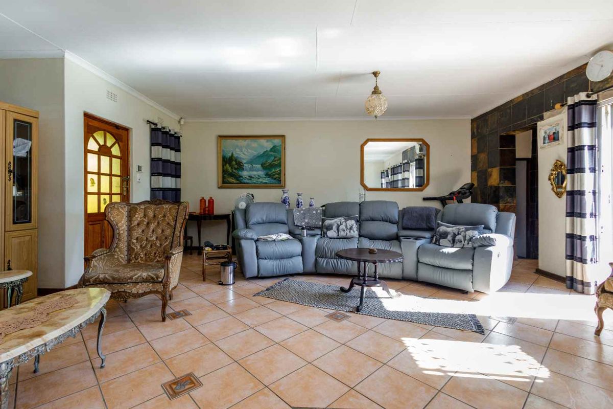 Spacious living room featuring tiled flooring, a stone accent wall, and a classic timber-framed entrance door.