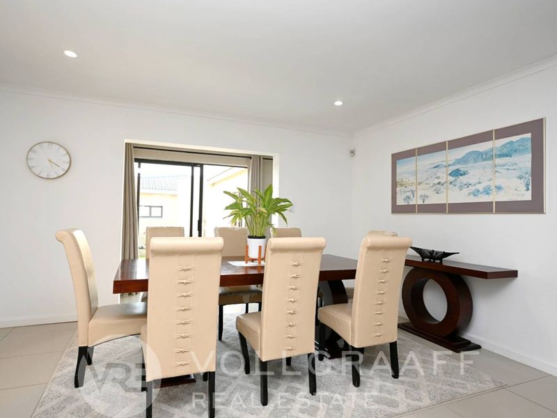 A bright and spacious dining room featuring tiled flooring, recessed downlighting, and a sliding glass door providing access to the outdoor area.