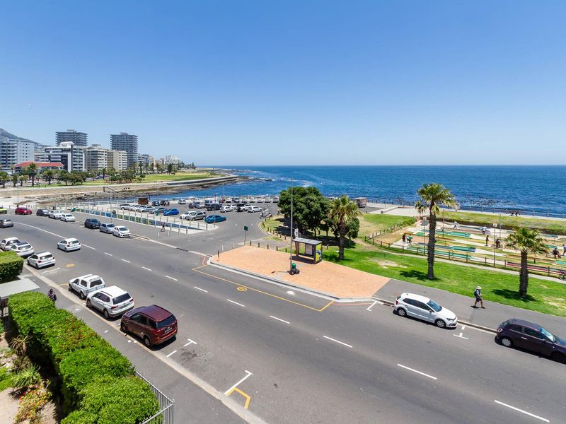 Elevated view overlooking the coastal road, public parking, park area, and the ocean horizon.