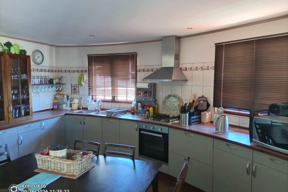 A functional kitchen featuring built-in cabinetry, a stainless steel extractor fan, a built-in oven with a gas hob, and a double sink.