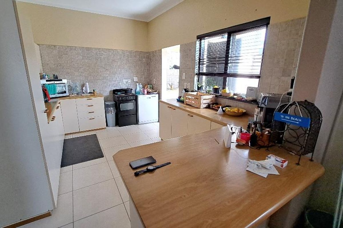 A functional kitchen featuring light-toned cabinetry, tiled splashbacks, a breakfast bar, and a built-in stove, offering a practical layout for daily meal preparation.