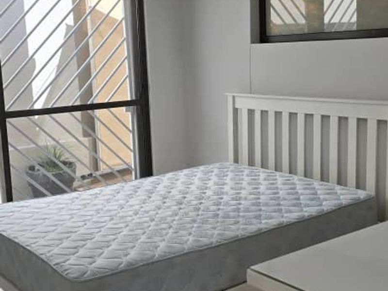 A bright bedroom featuring tiled flooring, an air conditioning unit, and a sliding door with security bars.