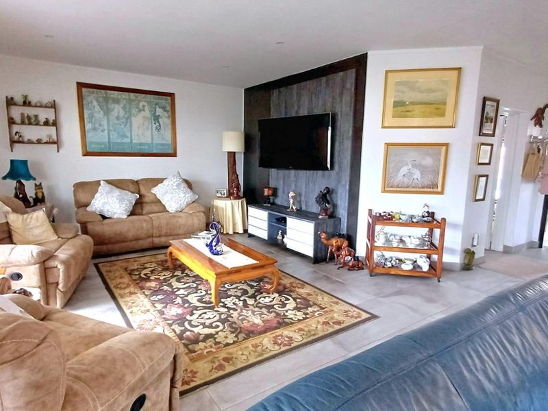 A spacious living room featuring tiled flooring, recessed downlighting, and a modern dark-toned feature wall.