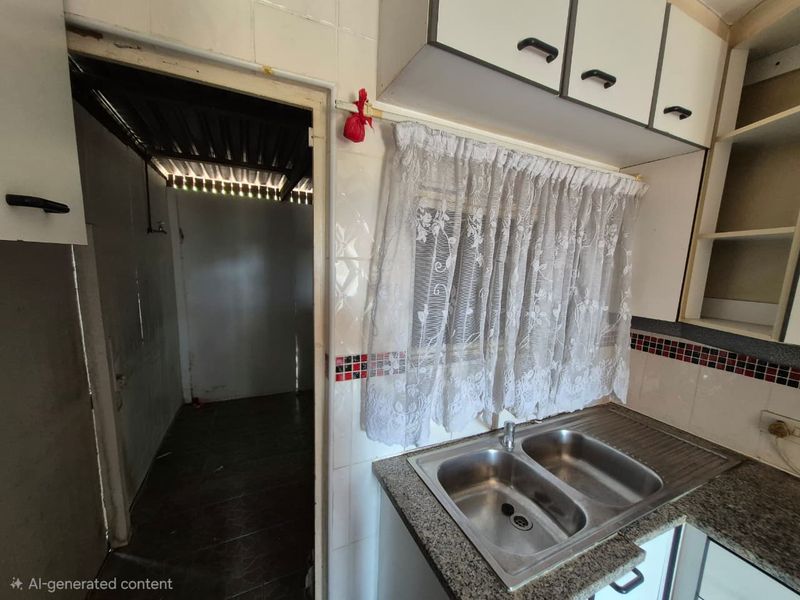 A dated kitchen area featuring a double bowl stainless steel sink, granite countertops, and overhead cabinetry, with an adjacent utility space.