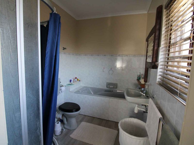 A functional bathroom featuring a built-in bathtub, wall-mounted basin, toilet, and a separate shower enclosure with tiled splashbacks.