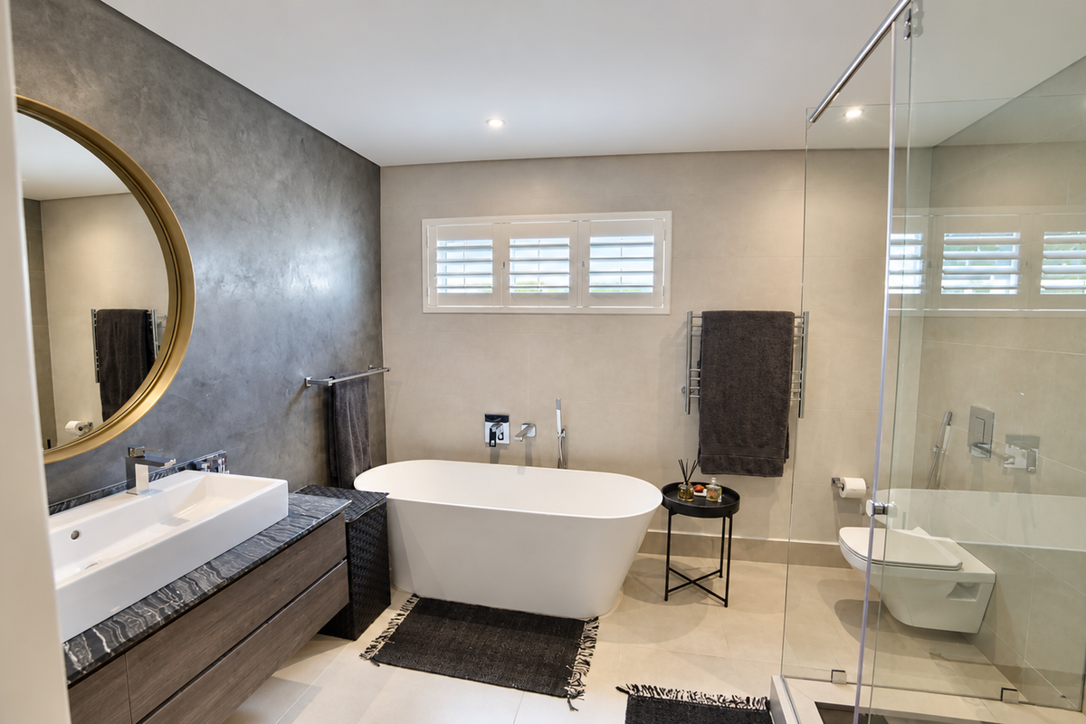 Modern bathroom featuring a sleek floating vanity, freestanding bathtub, glass-enclosed shower, wall-mounted toilet, and elegant plantation shutters.