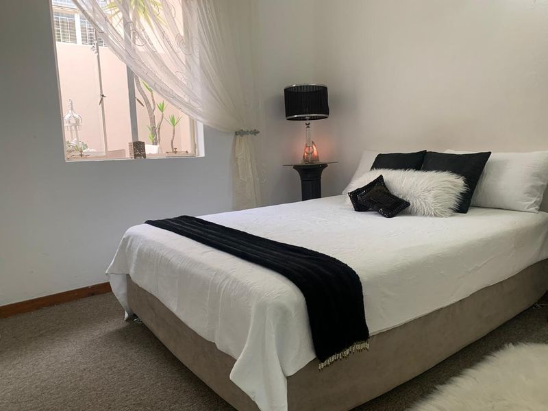A cozy bedroom featuring neutral wall finishes, carpeted flooring, and a window providing natural light.
