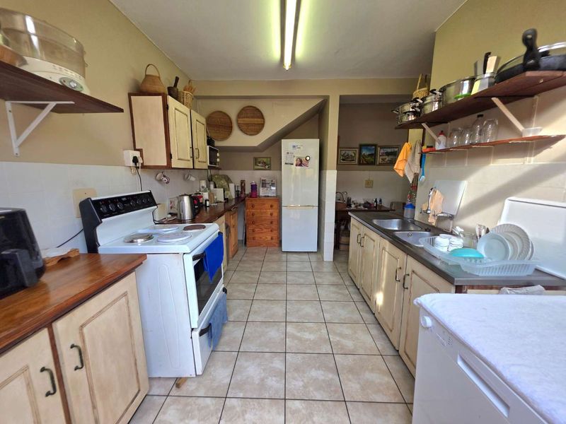 A functional kitchen featuring tiled flooring, a double stainless steel sink, and ample built-in cabinetry with a classic layout.