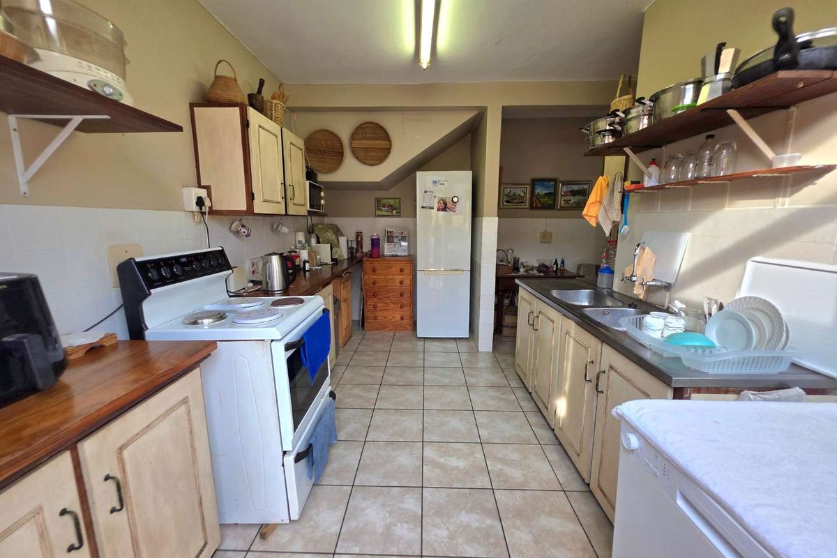 A functional kitchen featuring tiled flooring, a double stainless steel sink, and ample built-in cabinetry with a classic layout.