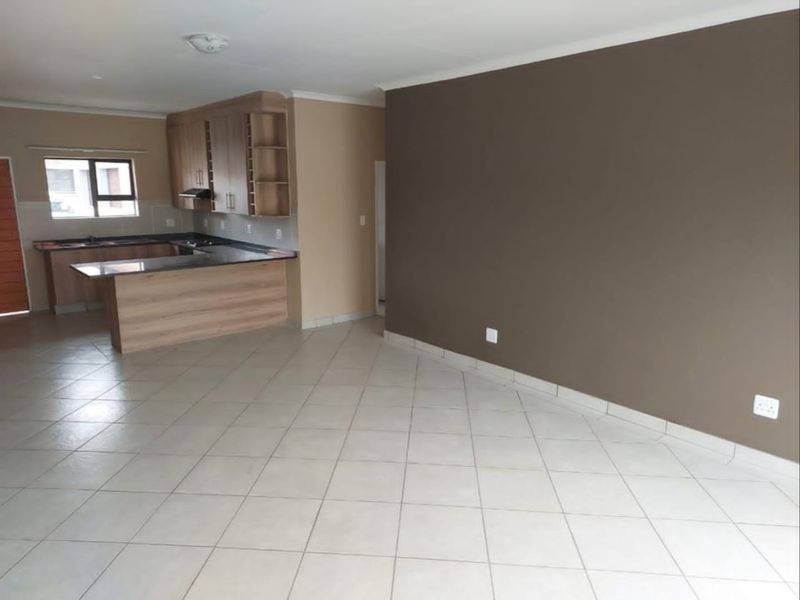 Spacious open-plan living area featuring tiled flooring and a functional kitchen with built-in cabinetry and laminate countertops.
