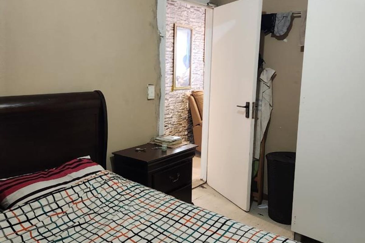 A bedroom featuring unfinished plasterwork around the door frame and visible wall surface damage, requiring cosmetic repairs and redecoration.