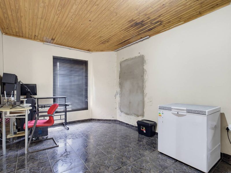 A small office space featuring a timber ceiling, tiled flooring, and venetian blinds, currently requiring cosmetic repairs to the walls and ceiling.