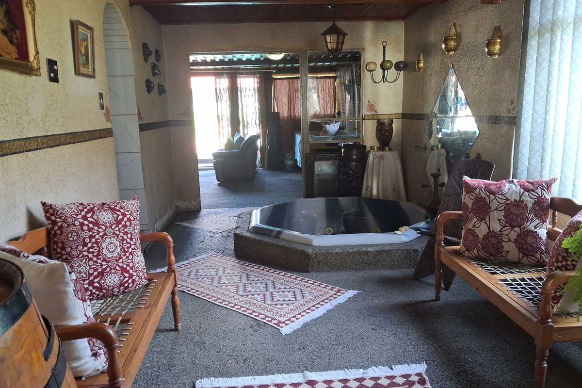 A unique indoor entertainment area featuring a built-in sunken spa bath, exposed timber ceiling beams, and direct access to an adjoining room.