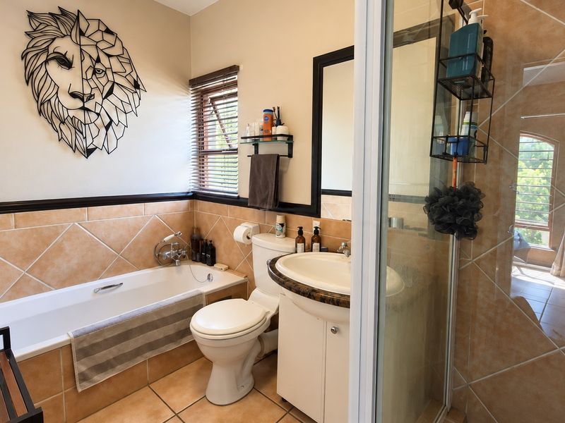 A functional bathroom featuring a bathtub, separate shower enclosure, vanity with basin, and neutral wall and floor tiling.