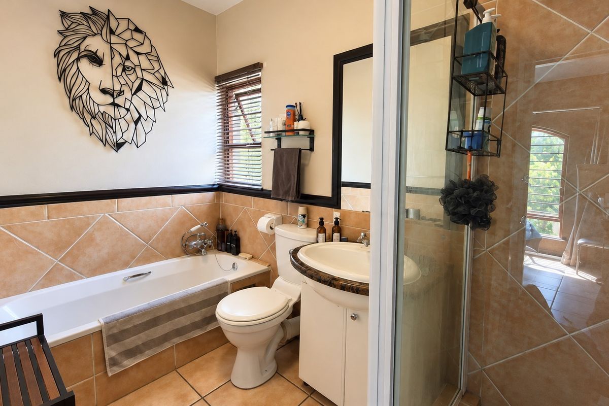 A functional bathroom featuring a bathtub, separate shower enclosure, vanity with basin, and neutral wall and floor tiling.
