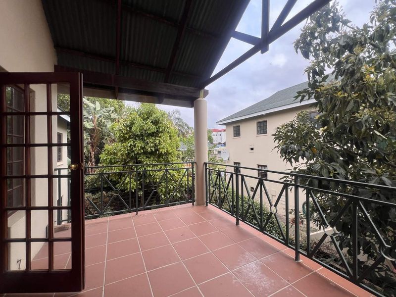 A covered balcony featuring tiled flooring, wrought iron railings, and direct access through french doors, offering an outdoor space for relaxation.
