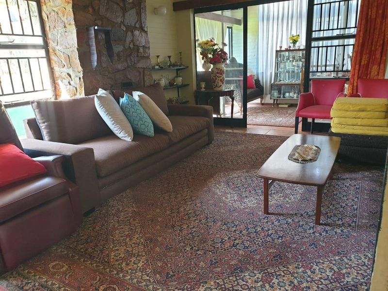 Spacious living room featuring a rustic stone feature wall, tiled flooring, and large sliding glass doors that open onto an adjacent sunroom area.