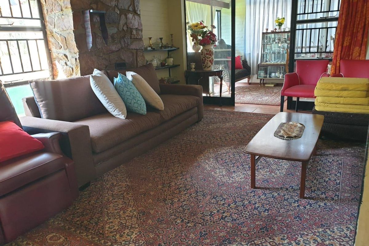 Spacious living room featuring a rustic stone feature wall, tiled flooring, and large sliding glass doors that open onto an adjacent sunroom area.