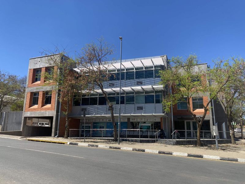 A modern three-story commercial office building featuring a combination of brick and glass facade, external sun louvers, and convenient street-level access.