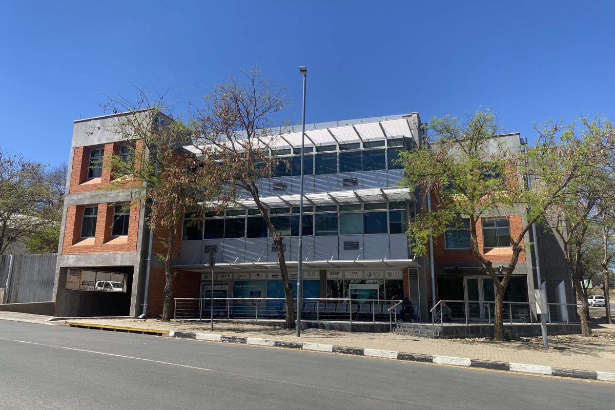 A modern three-story commercial office building featuring a combination of brick and glass facade, external sun louvers, and convenient street-level access.