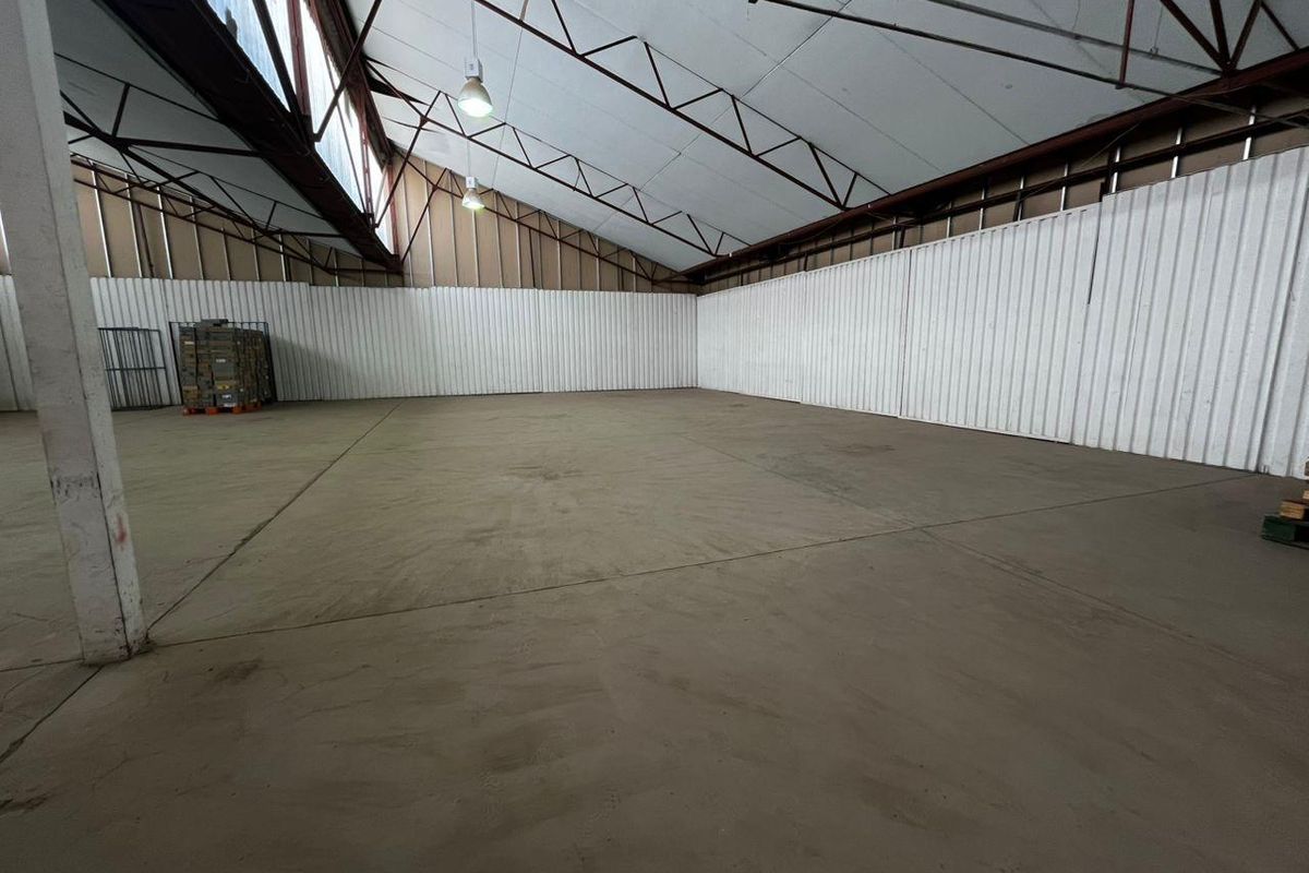 Spacious industrial utility area featuring high ceilings with exposed steel trusses, corrugated metal wall cladding, and durable concrete flooring.