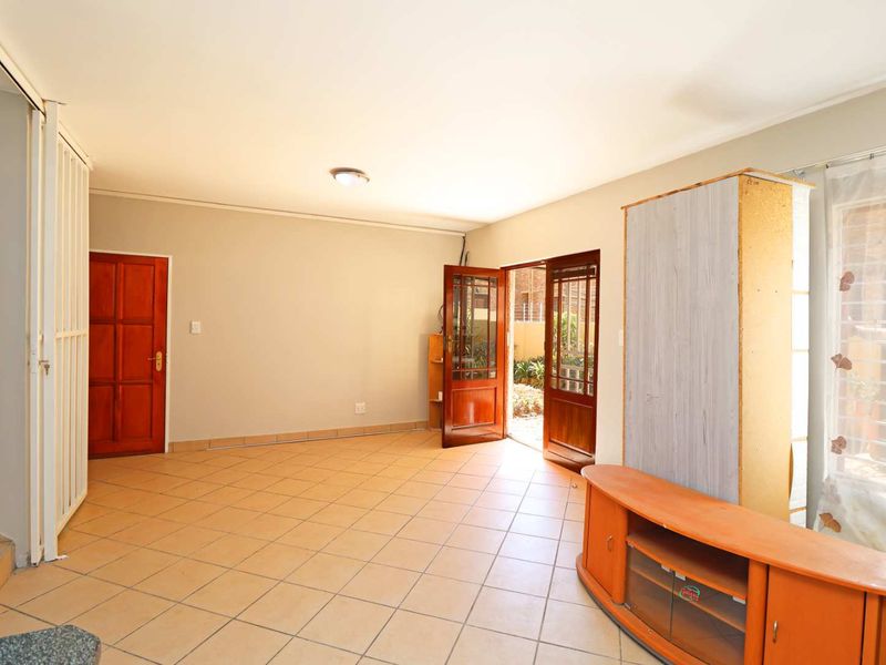 A living room featuring tiled flooring, a wooden door, and a sliding door providing access to the exterior.