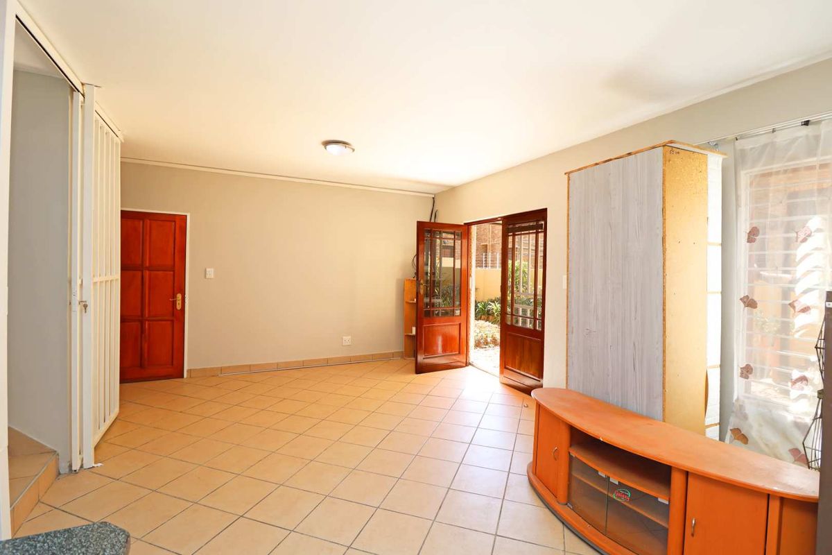 A living room featuring tiled flooring, a wooden door, and a sliding door providing access to the exterior.