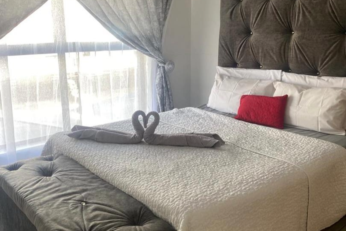 A well-lit bedroom featuring a large window with natural light and neutral wall finishes.