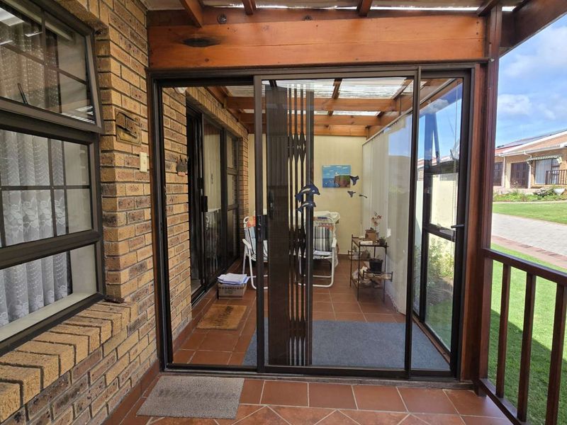 A covered patio area featuring tiled flooring, timber pergola structure, and sliding glass doors providing access to the interior living space.