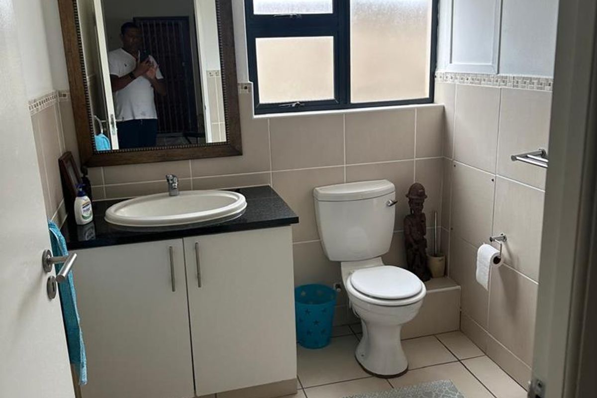 A functional bathroom featuring a vanity cabinet with a countertop basin, toilet, and neutral tiled finishes throughout.